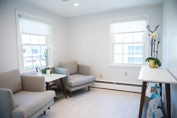 Sunlit lobby with a soft gray sofa, armchair and coffee table