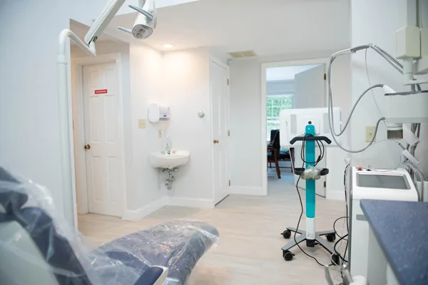 Inside a treatment room with a chair, overhead light and digital equipment