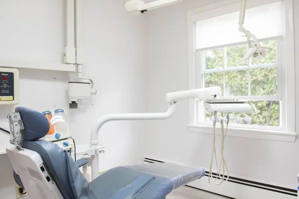 Treatment room with a dental chair beside a bright window